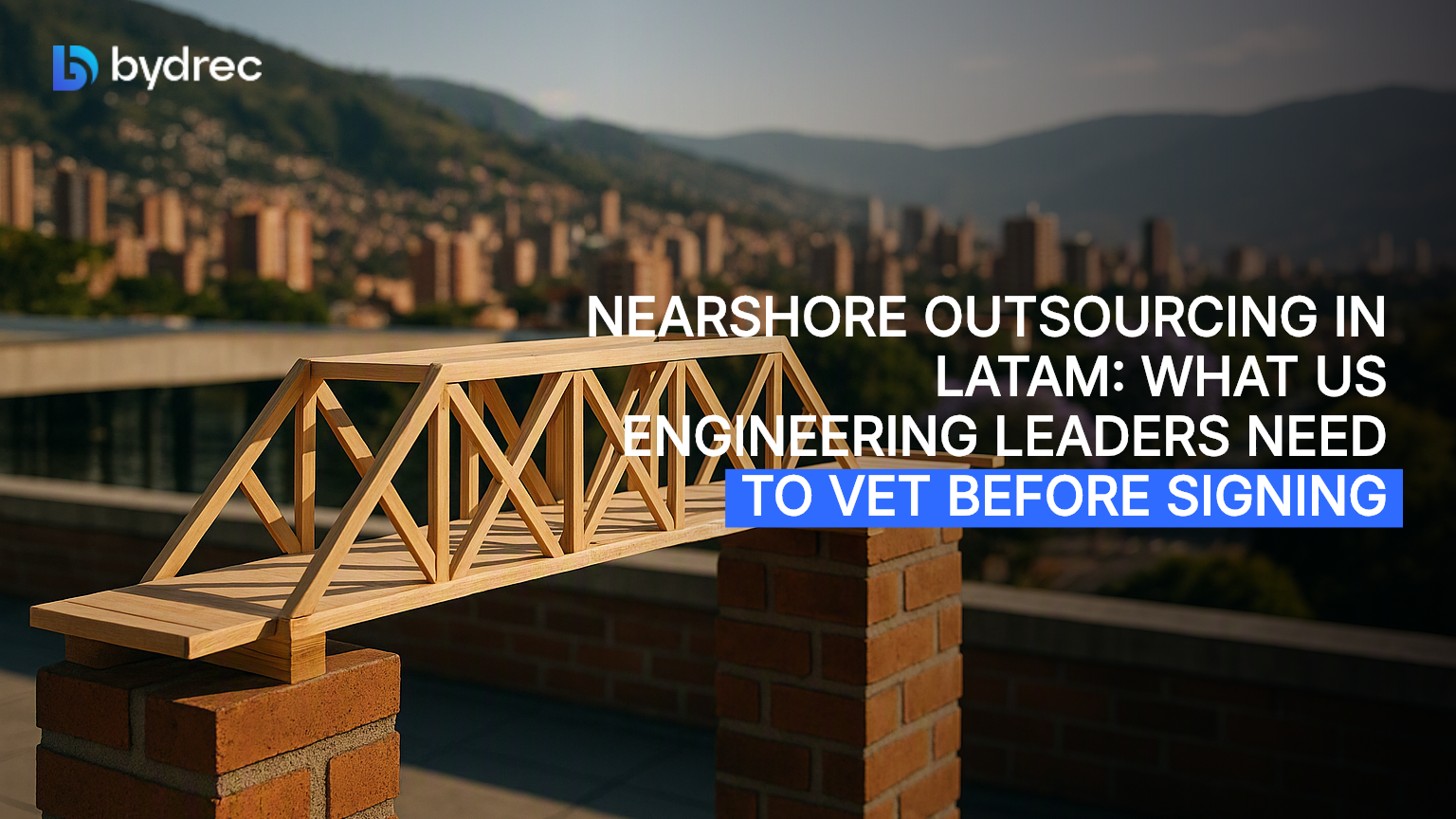 Unfinished wooden bridge model on a Medellín rooftop ledge at golden hour, city hills visible beyond.